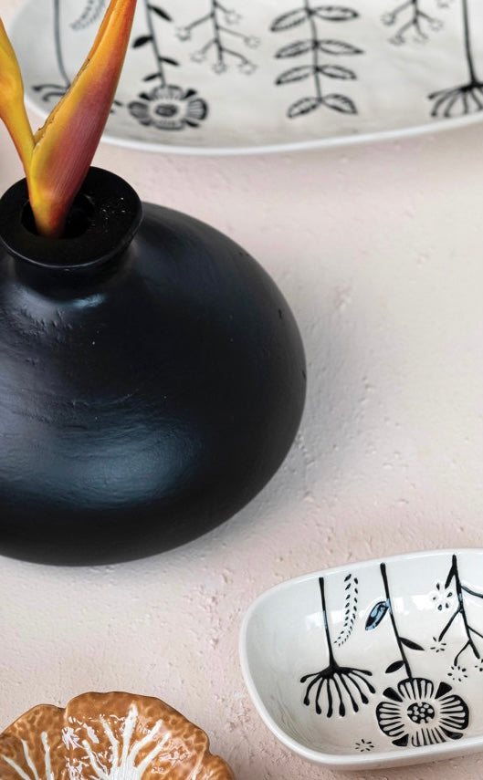 Hand-Painted Stoneware Platter with Embossed Flowers shown on a table.