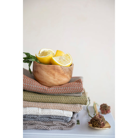 Small acacia wood bowl sitting on stack of kitchen towels.
