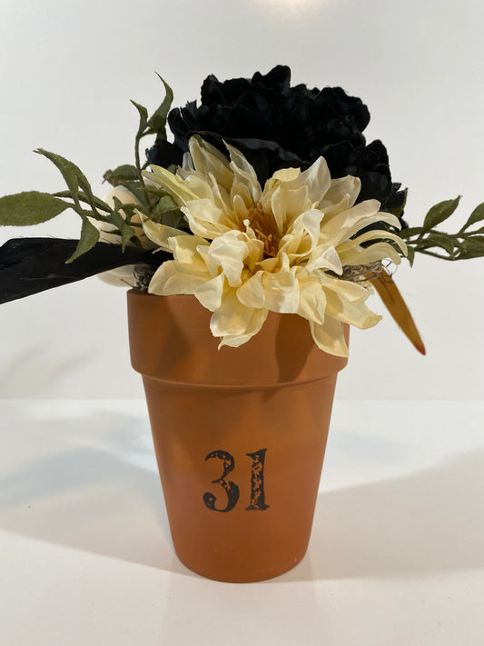 Halloween floral with black flower and white pumpkin in clay pot. Front view.