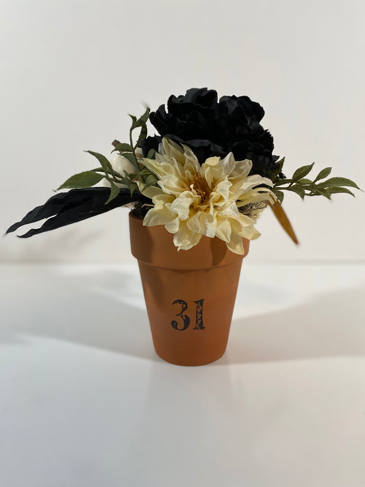 Halloween floral with black flower and white pumpkin in clay pot.